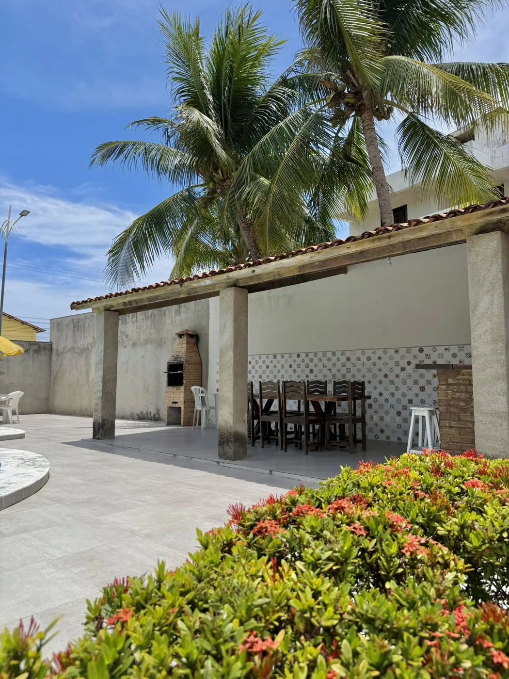 Área gourmet coberta com churrasqueira de alvenaria e mesa de madeira