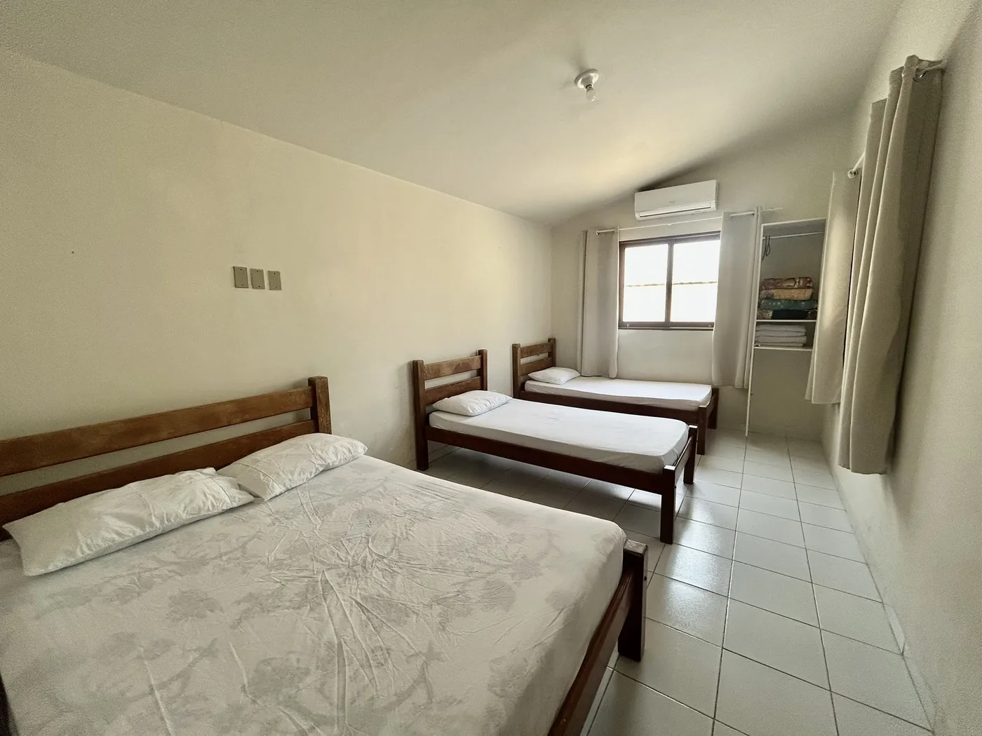 Quarto com cama de casal, duas camas de solteiro e ar-condicionado split
